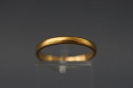 A yellow metal D shape wedding band with personal inscription. Tests indicate 22ct gold.