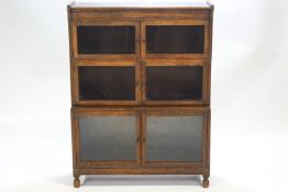 An oak sectional bookcase on turned legs set with three staggered two door glazed units,