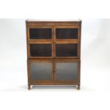 An oak sectional bookcase on turned legs set with three staggered two door glazed units,