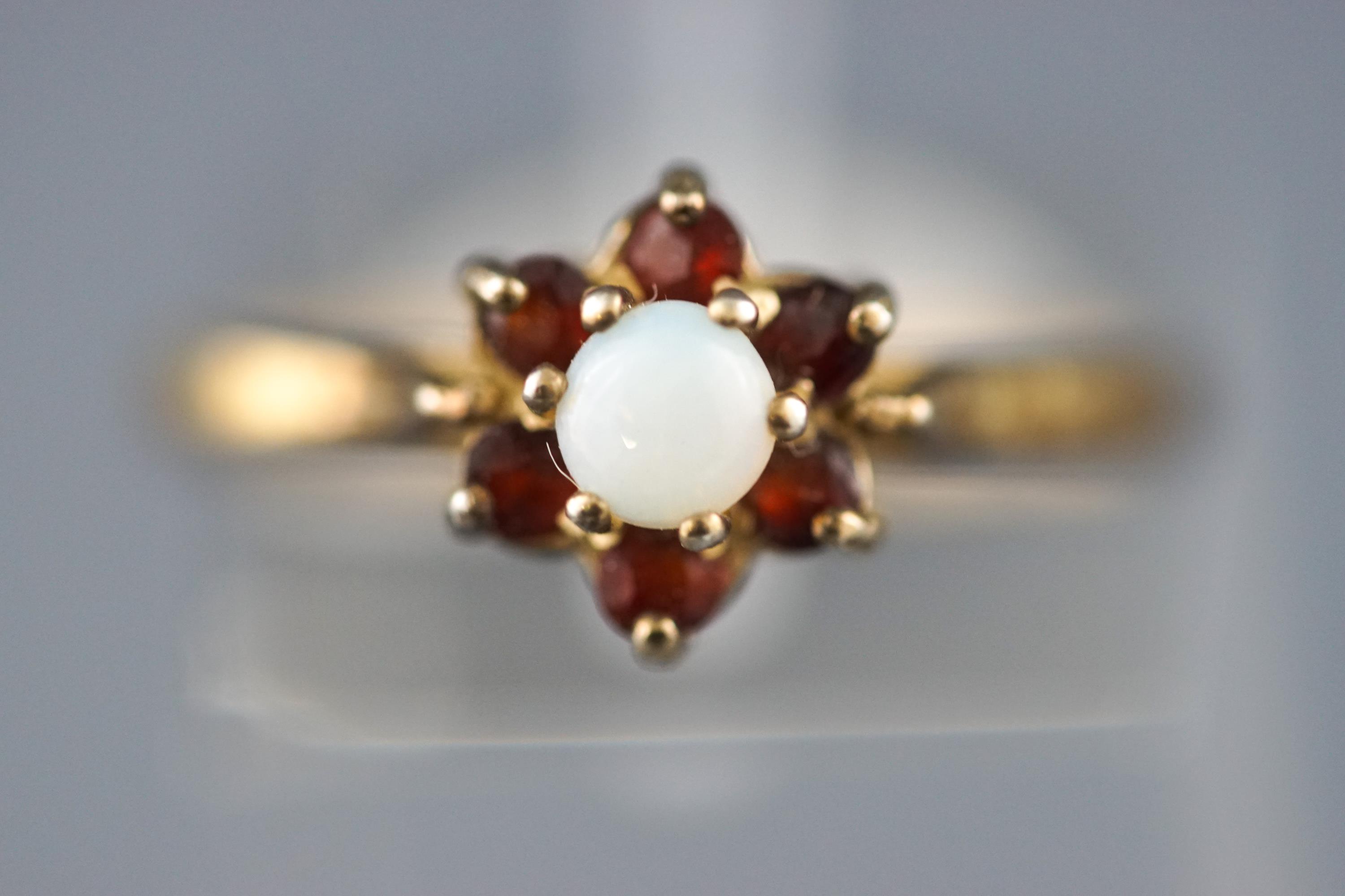 A yellow metal cluster ring set with commercial opal and garnets.