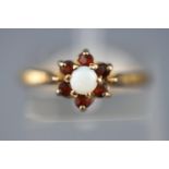 A yellow metal cluster ring set with commercial opal and garnets.