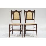 A pair of Edwardian mahogany salon chairs with inlaid decoration to the padded backs