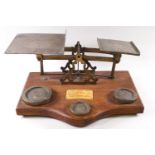 A set of oak and brass inlaid letter and parcel scales, set with three weights to the base,