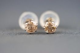 A modern white metal pair of single stone stud earrings.