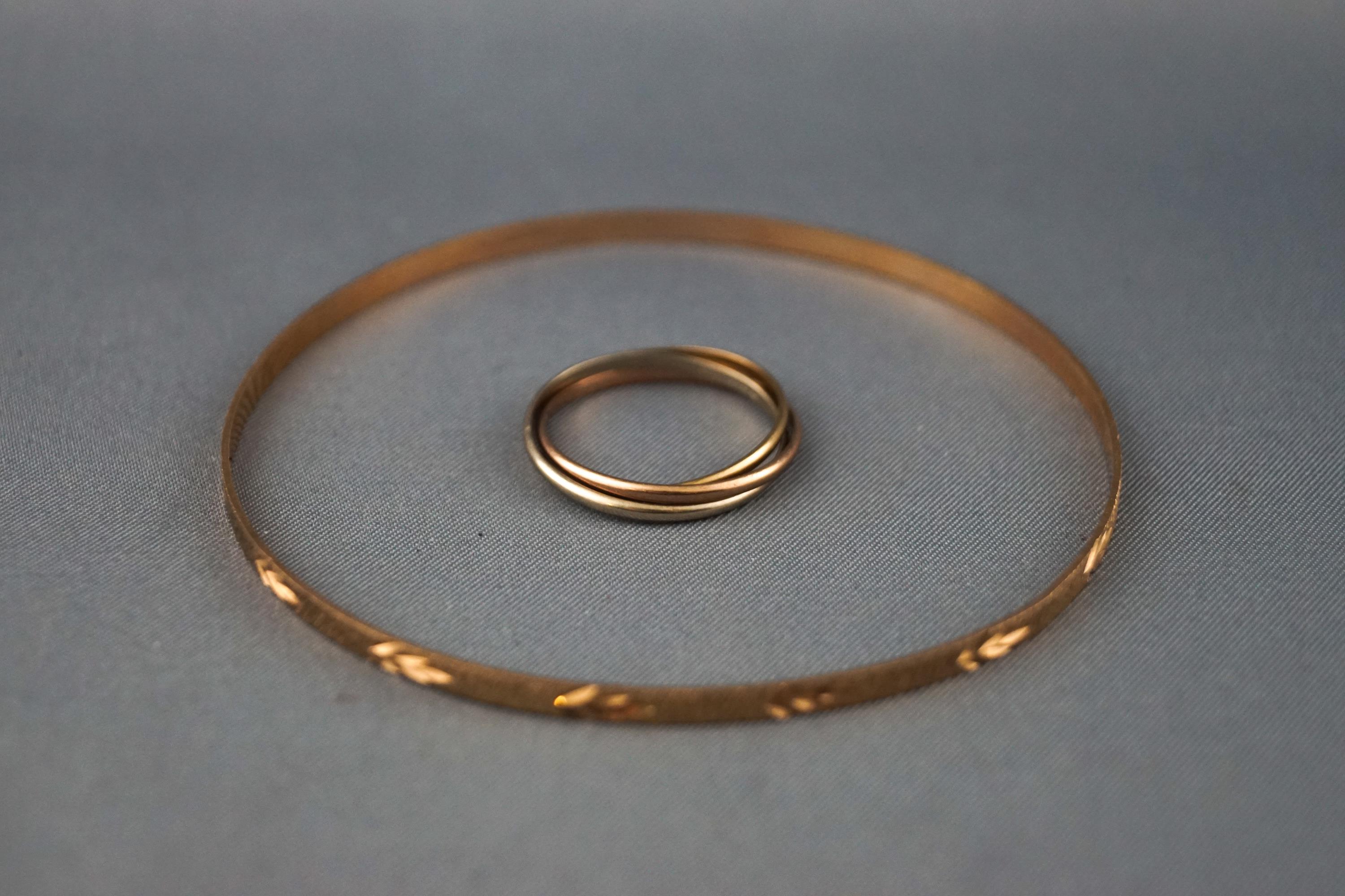 A yellow metal slave bangle together with a yellow/white/rose metal Russian wedding ring