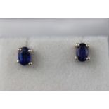 A modern white metal pair of single stone stud earrings. Each set with an oval faceted cut kyanite.