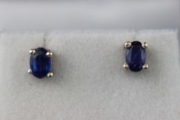 A modern white metal pair of single stone stud earrings. Each set with an oval faceted cut kyanite.