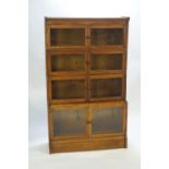 An oak sectional bookcase on a plain base with four staggered two glazed door units,