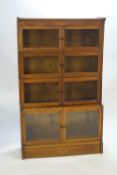 An oak sectional bookcase on a plain base with four staggered two glazed door units,