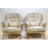 A pair of Ercol bent beech wood Windsor style arm chairs with attached pads,