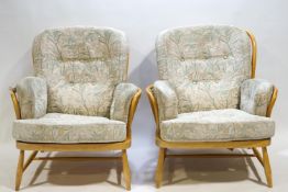 A pair of Ercol bent beech wood Windsor style arm chairs with attached pads,