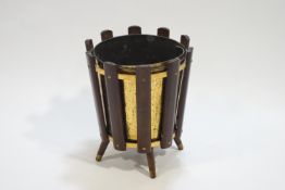 A retro styled brass planter/coal bucket in a hardwood frame, raised on four legs,