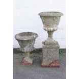A pair of composite stone campana form garden urns, one on a squared socle,
