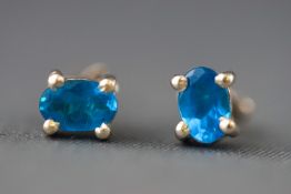 A modern white metal pair of single stone stud earrings.