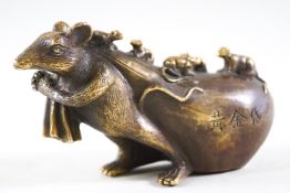 A signed Japanese metal figure of a rat pulling a Hotei sack covered in its young,