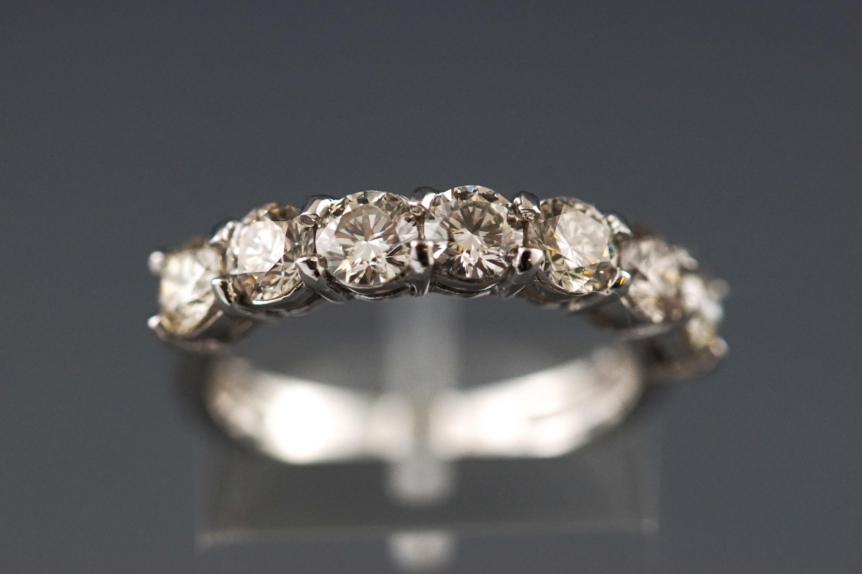 A modern white metal half hoop diamond ring.