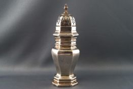 A silver caster of flattened octangular baluster form with pull off pierced lid set with an urn