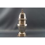 A silver caster of flattened octangular baluster form with pull off pierced lid set with an urn