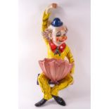 A 1960's glazed terracotta shelf figure of a clown in a yellow suit