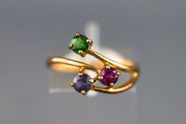 A yellow metal dress ring set with a peridot, rhodolite garnet and an amethyst.