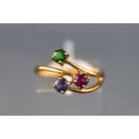 A yellow metal dress ring set with a peridot, rhodolite garnet and an amethyst.