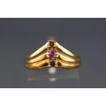 A yellow metal three stone ring set with pink sapphire and two champagne diamonds.