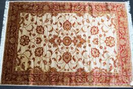 A machine woven Keshan carpet with scrolling flowers on a beige ground within one wide border,