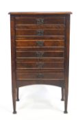 A stained wood music cabinet of upright rectangular form with plain top over six fall front drawers