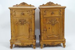 A pair of French pine contraposed bedside cupboards with shell carved back rail