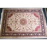A machine woven Keshan carpet with central medallion and scrolling flowers on a beige ground