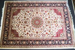 A machine woven Keshan carpet with central medallion and scrolling flowers on a beige ground