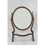 A mahogany framed oval swing mirror of traditional form