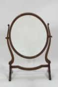 A mahogany framed oval swing mirror of traditional form