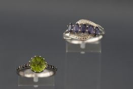 A white metal single stone peridot ring with gem set shoulders