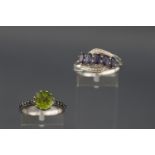 A white metal single stone peridot ring with gem set shoulders