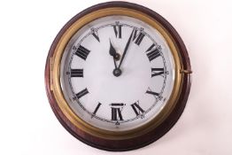 A brass cased ships timepiece on a mahogany panel with white enamel Roman dial, clock 18cm diameter,