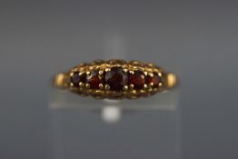 A yellow metal half hoop ring set with five graduated garnets. Hallmarked 9ct gold, London.