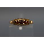 A yellow metal half hoop ring set with five graduated garnets. Hallmarked 9ct gold, London.