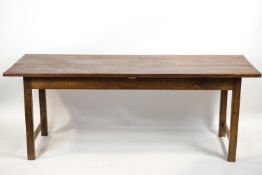 A plain elm refectory table raised on plain square legs with end stretchers,