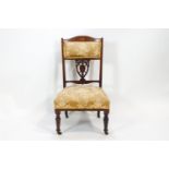 An Edwardian walnut salon/nursing chair with shaped back rail inlaid with a central patera