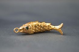 A yellow metal articulated fish pendant with cabochon green eyes. Acid tests inconclusive 4.9 grams