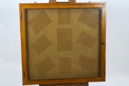 An oak framed square, shallow wall cabinet with hinged, glazed door,