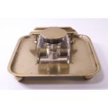 A brass ink bottle stand with pen rest, raised on four ball feet,