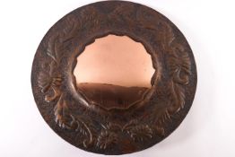 An Arts and crafts copper round framed mirror with repousse floral and foliate decoration