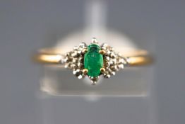 A yellow metal cluster ring set with an oval emerald single cut diamonds.