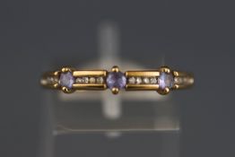 A yellow metal dress ring set with tanzanites and single cut diamonds.