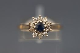 A yellow metal cluster ring. Set with a central sapphire and surrounded by ten diamonds