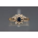 A yellow metal cluster ring. Set with a central sapphire and surrounded by ten diamonds