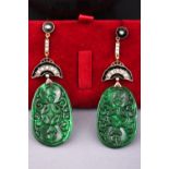 A yellow metal pair of drop earrings. Each having a large oval pierced jade drop.