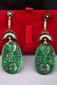 A yellow metal pair of drop earrings. Each having a large oval pierced jade drop.